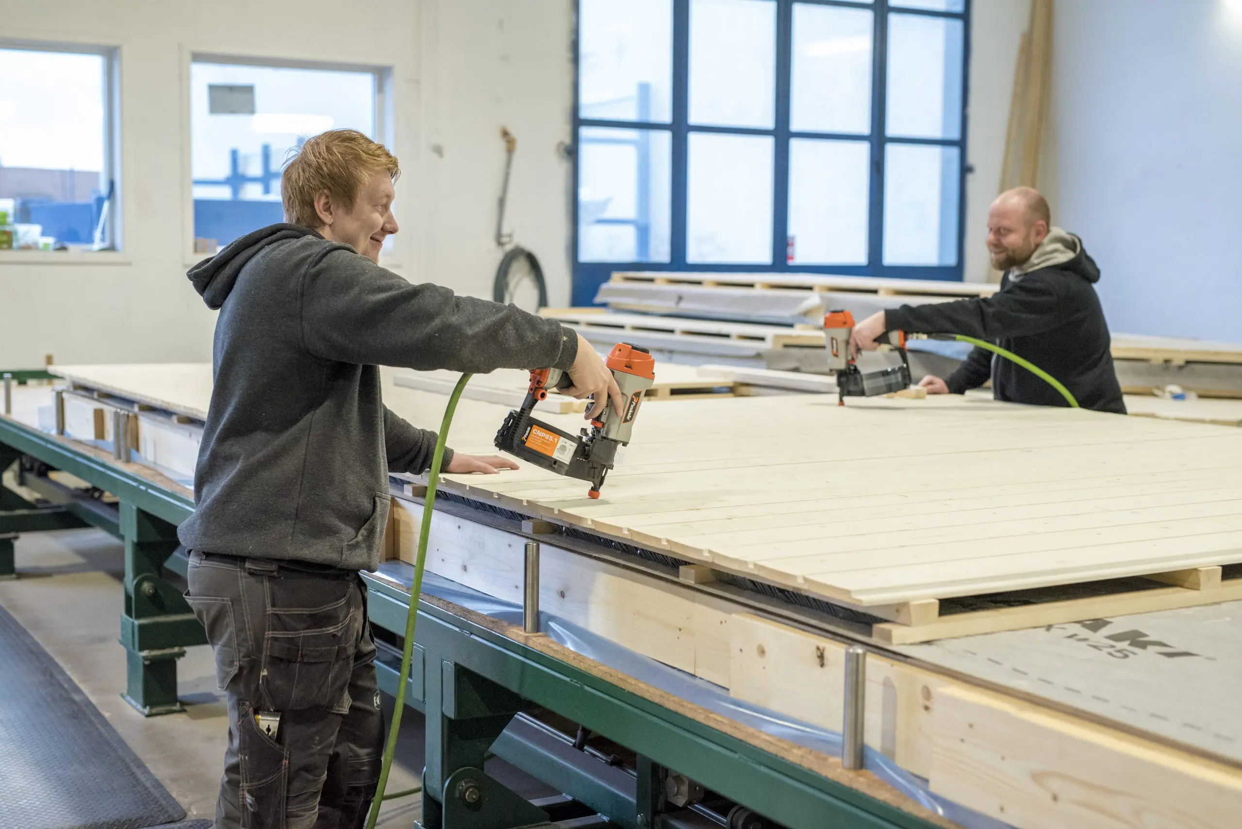 bildet viser to menn som snekrer et element og smiler