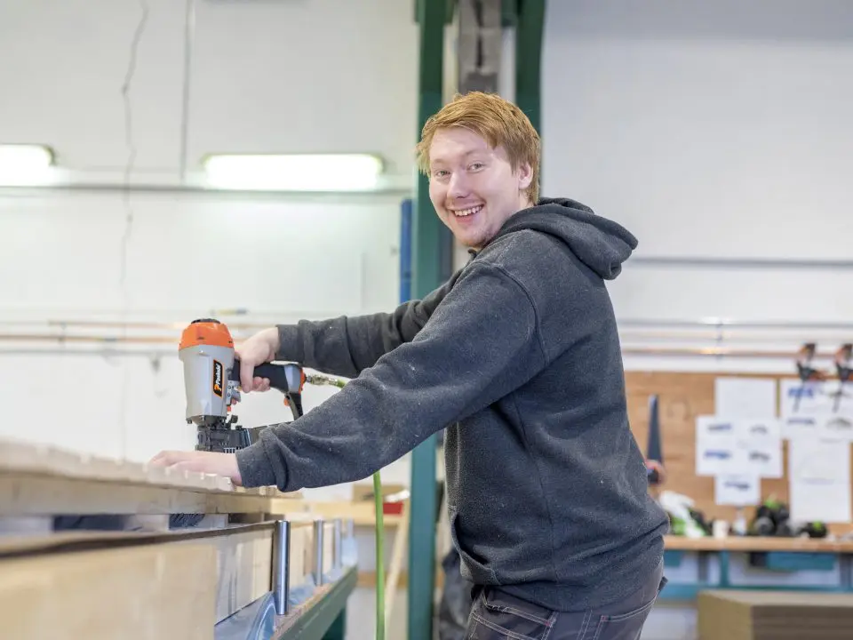 bildet viser en mann som smiler og snekrer