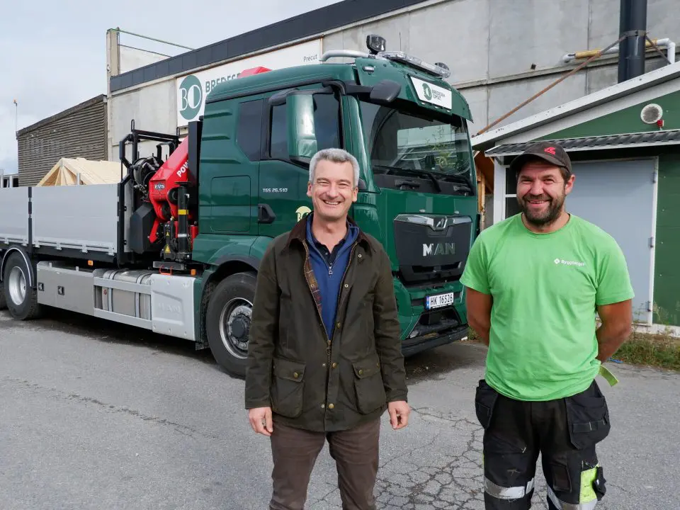 bildet viser to blide menn foran en lastebil med takstoler